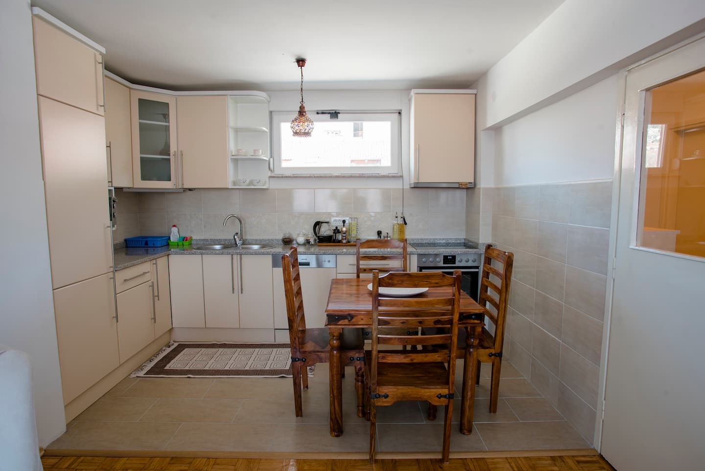 Fitted kitchen with a hob, sink and wooden dining table for meals in