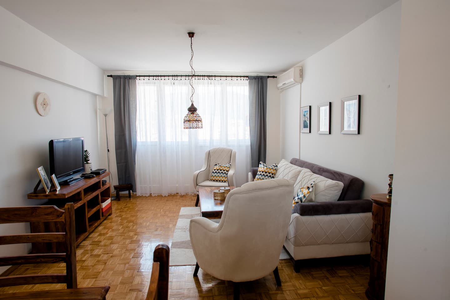 Living room with television, armchairs and a curtained window