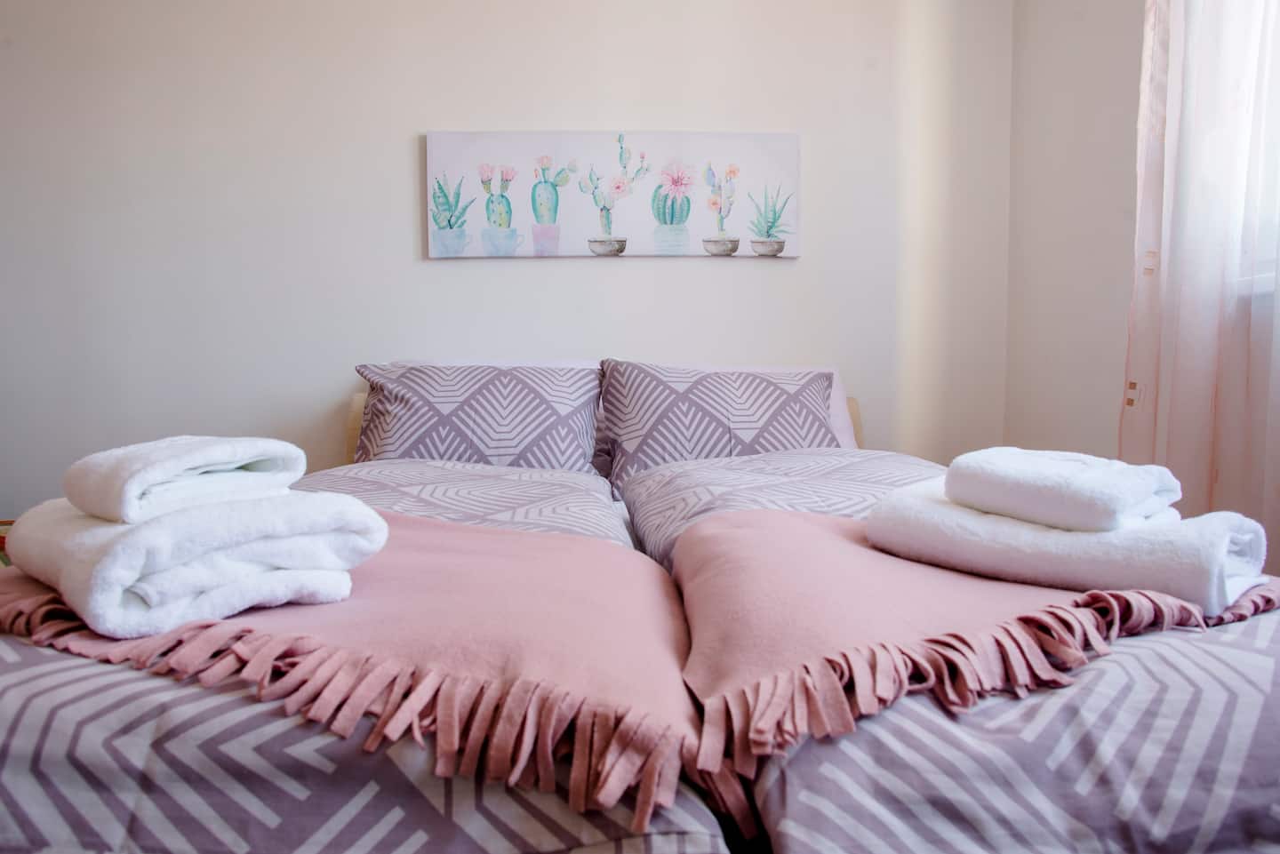 Bedroom with made-up bedding and folded towels laid out for guests